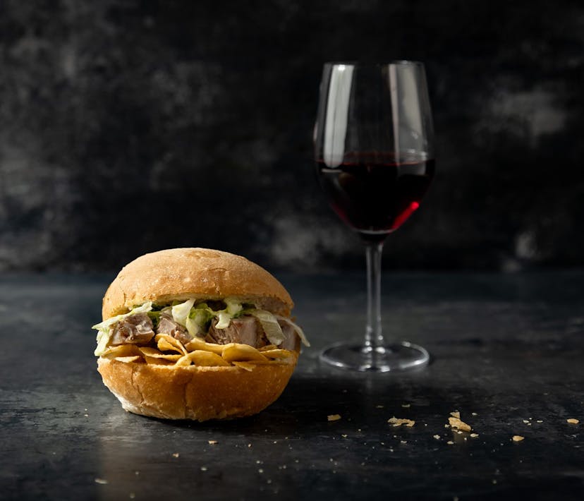 A pork bun with a glass of red wine.