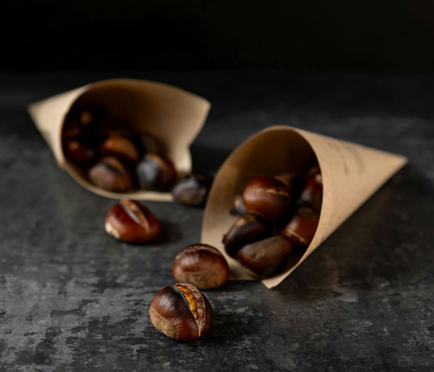 Two paper cones filled with roasted chestnuts.