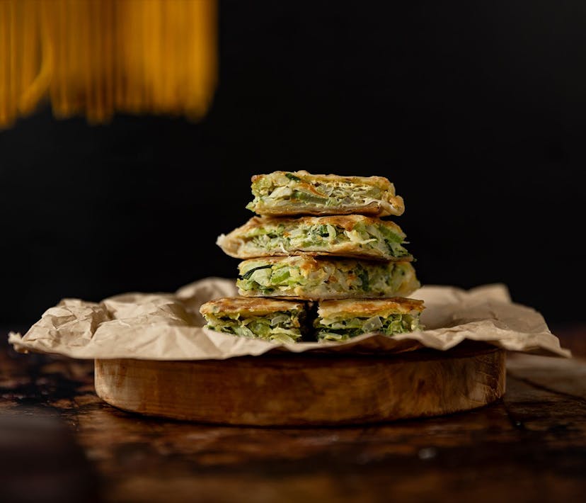 A stack of martabak - a golden savoury pancake stuffed with vegetables.