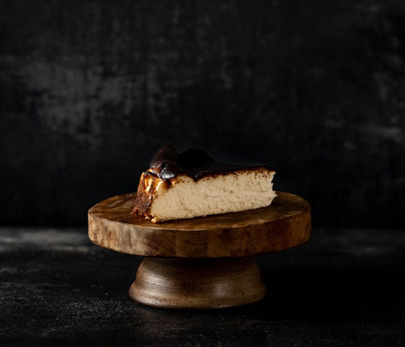 A slice of Basque Cheesecake sitting on a wooden pedestal.
