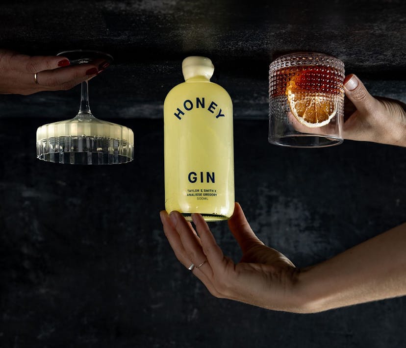An upside-down image of a Honey Gin bottle, and two cocktails.
