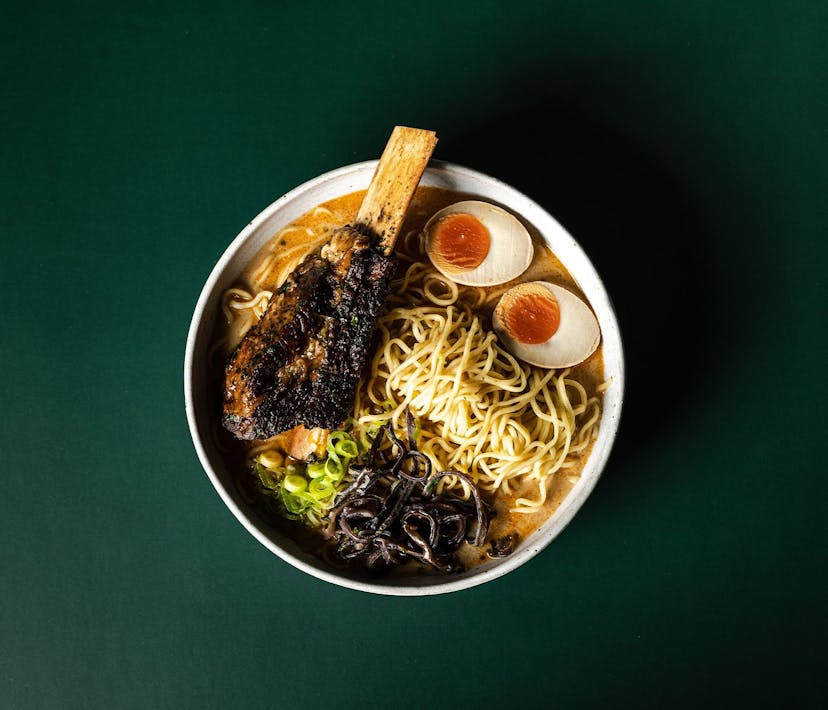 A packed bowl of beef ramen featuring noodles, egg, beef and vegetables.