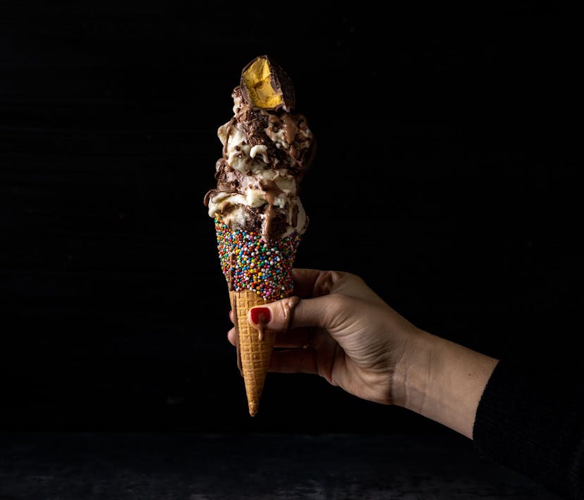 A decadent ice-cream cone stacked with sauces, honeycomb and rainbow sprinkles.