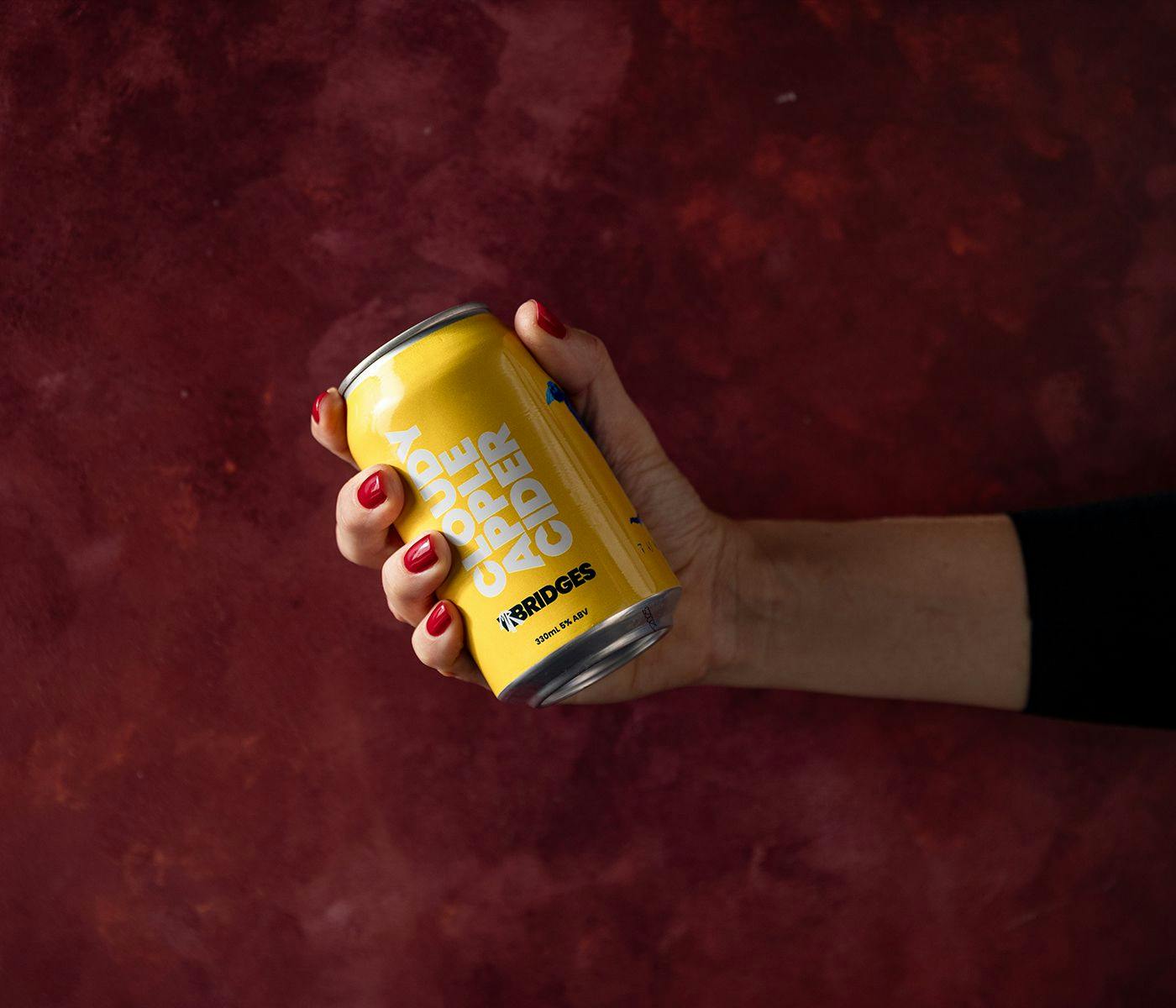 A hand grasps a can of Cloudy Apple Cider.