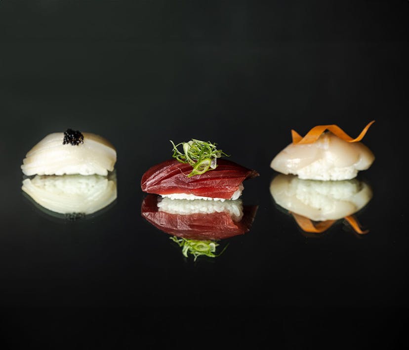 Three different nigiri sushis on a glass reflective surface.