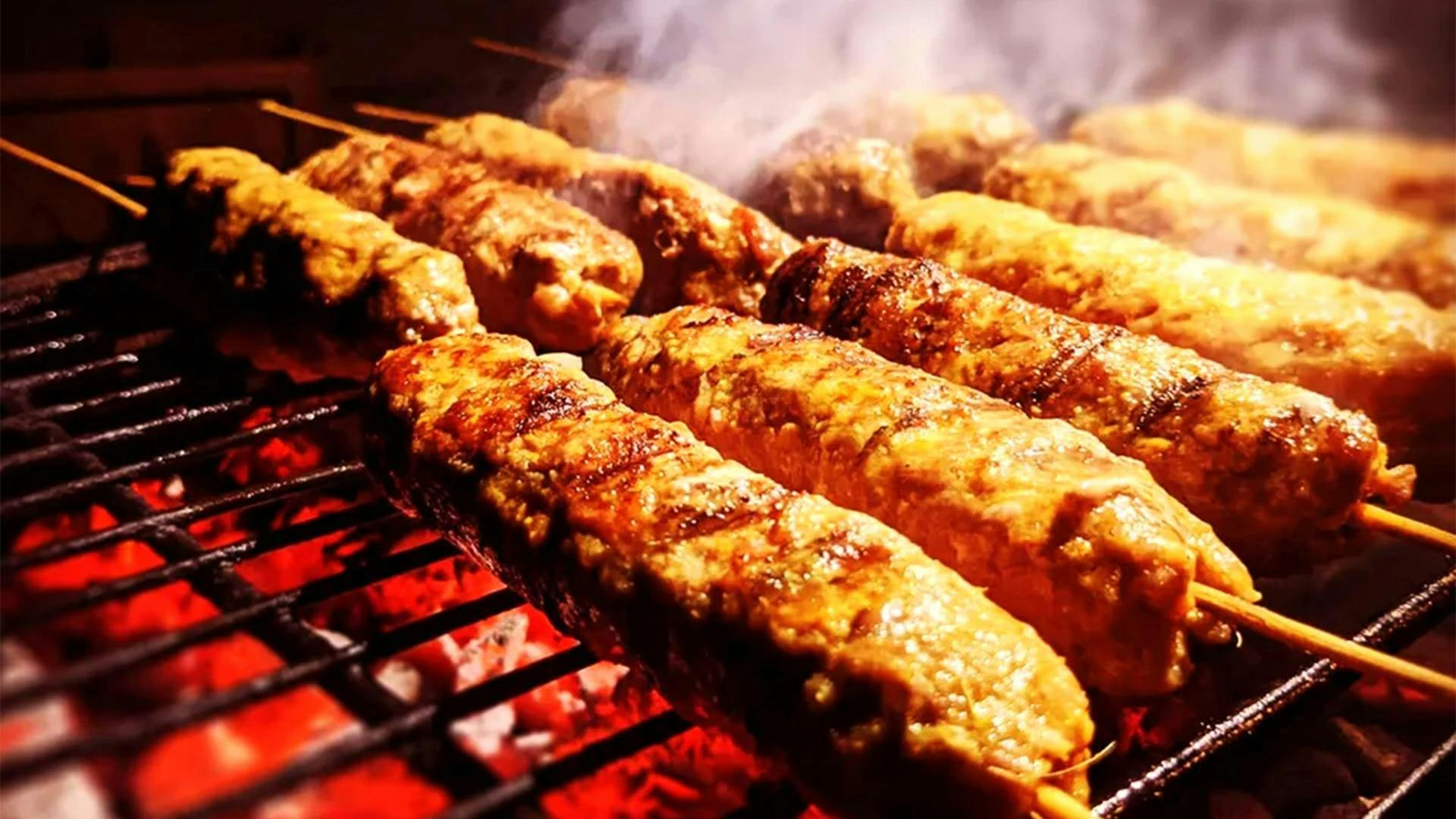 Meat skewers on a grill with red hot coals and smoke