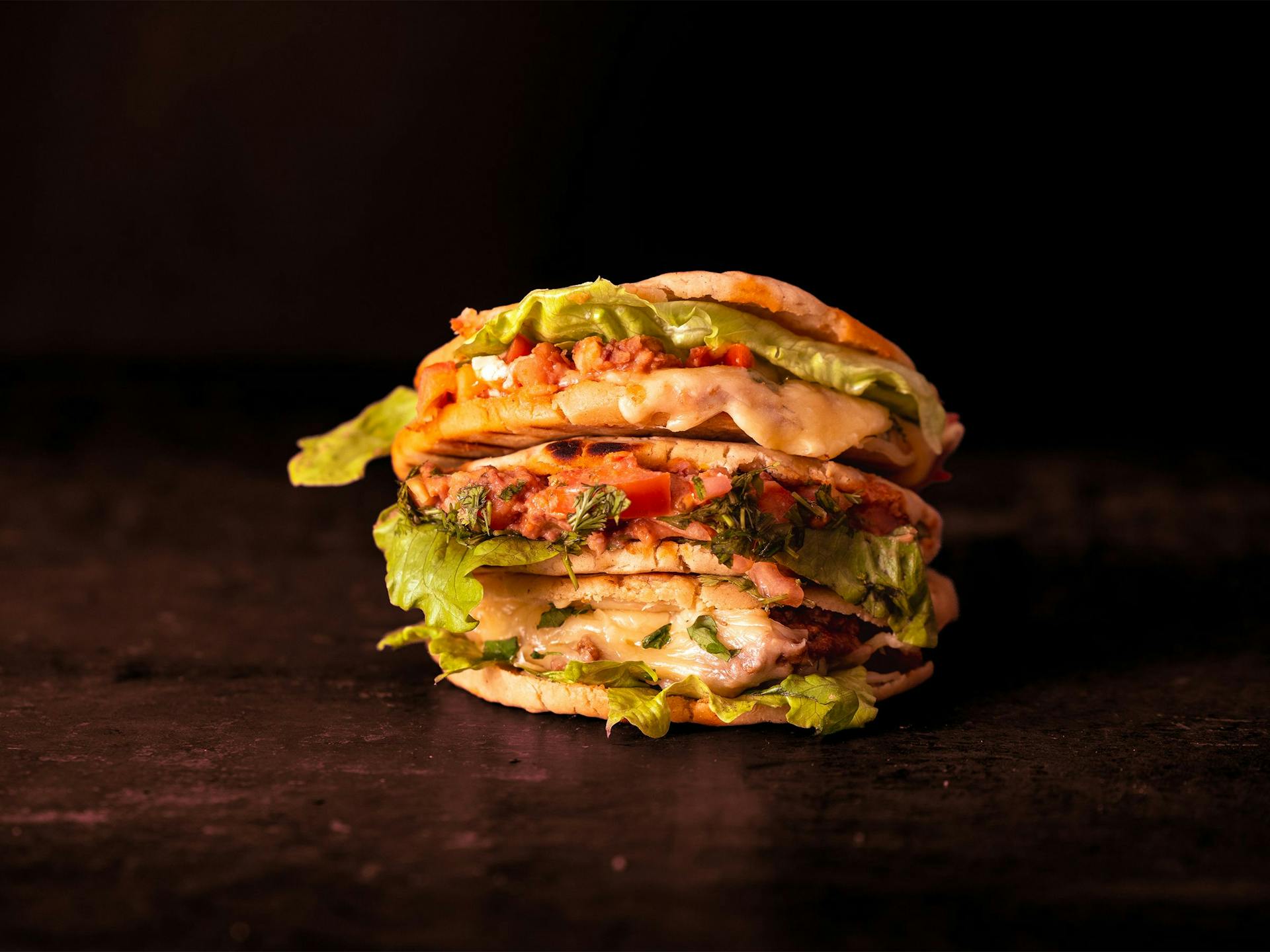 Three arepas stacked on top of each other in front of a black background
