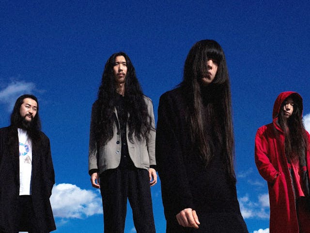 Four members of Bo Ningen pose, a lightly clouded blue sky their backdrop.