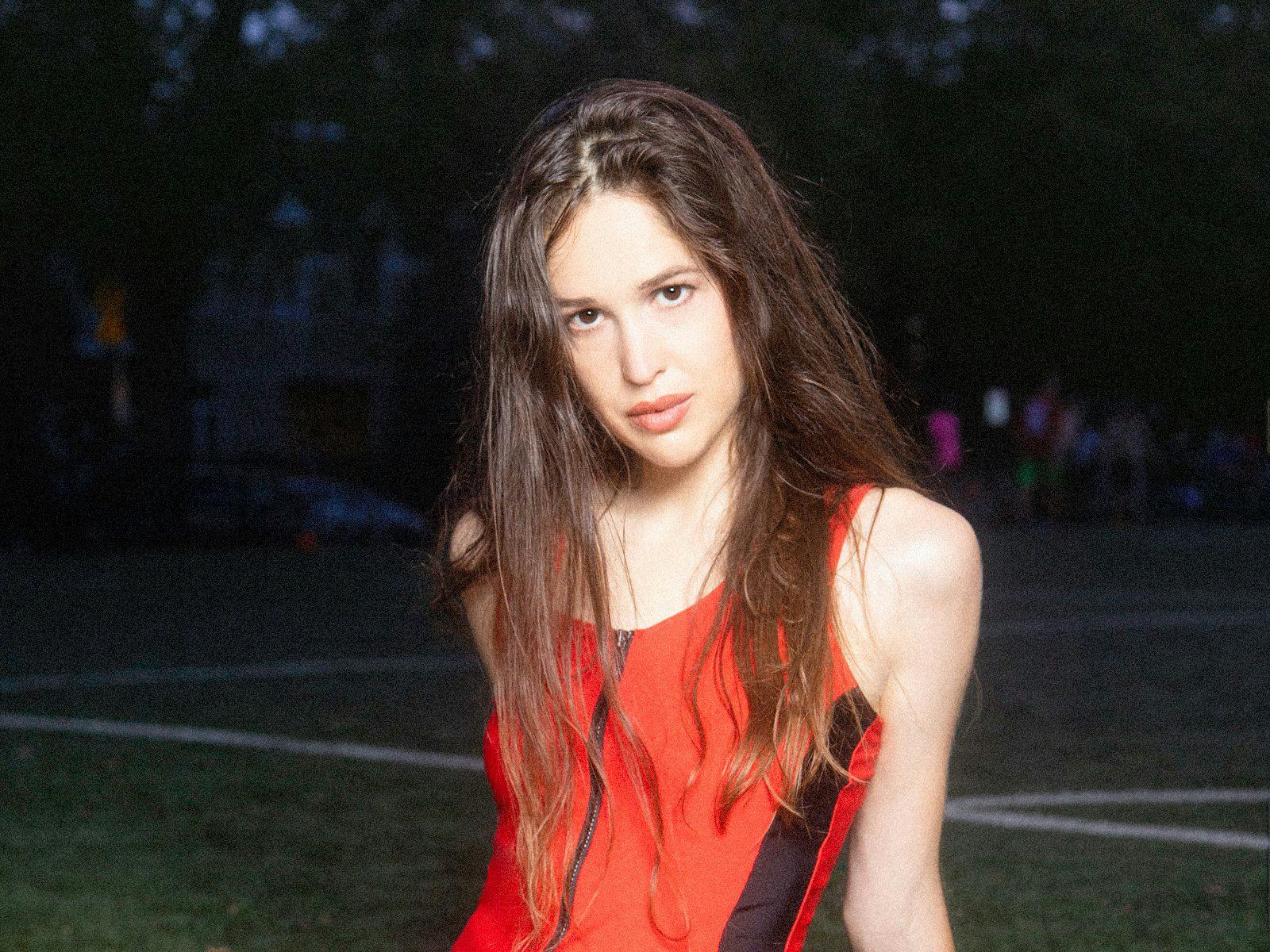 Marie Davidson sits on an outdoor sports field.