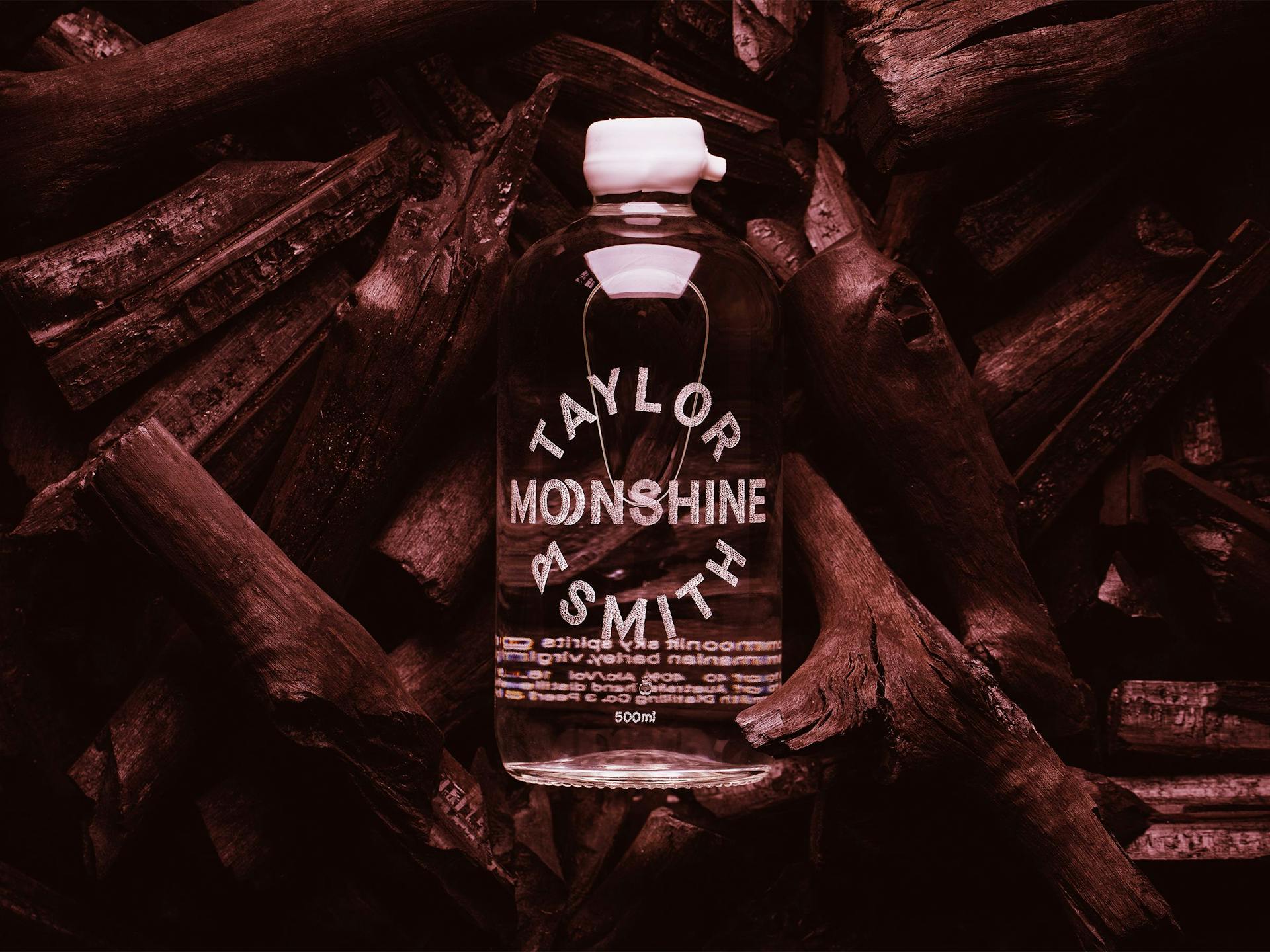 A bottle of craft moonshine sitting on wood