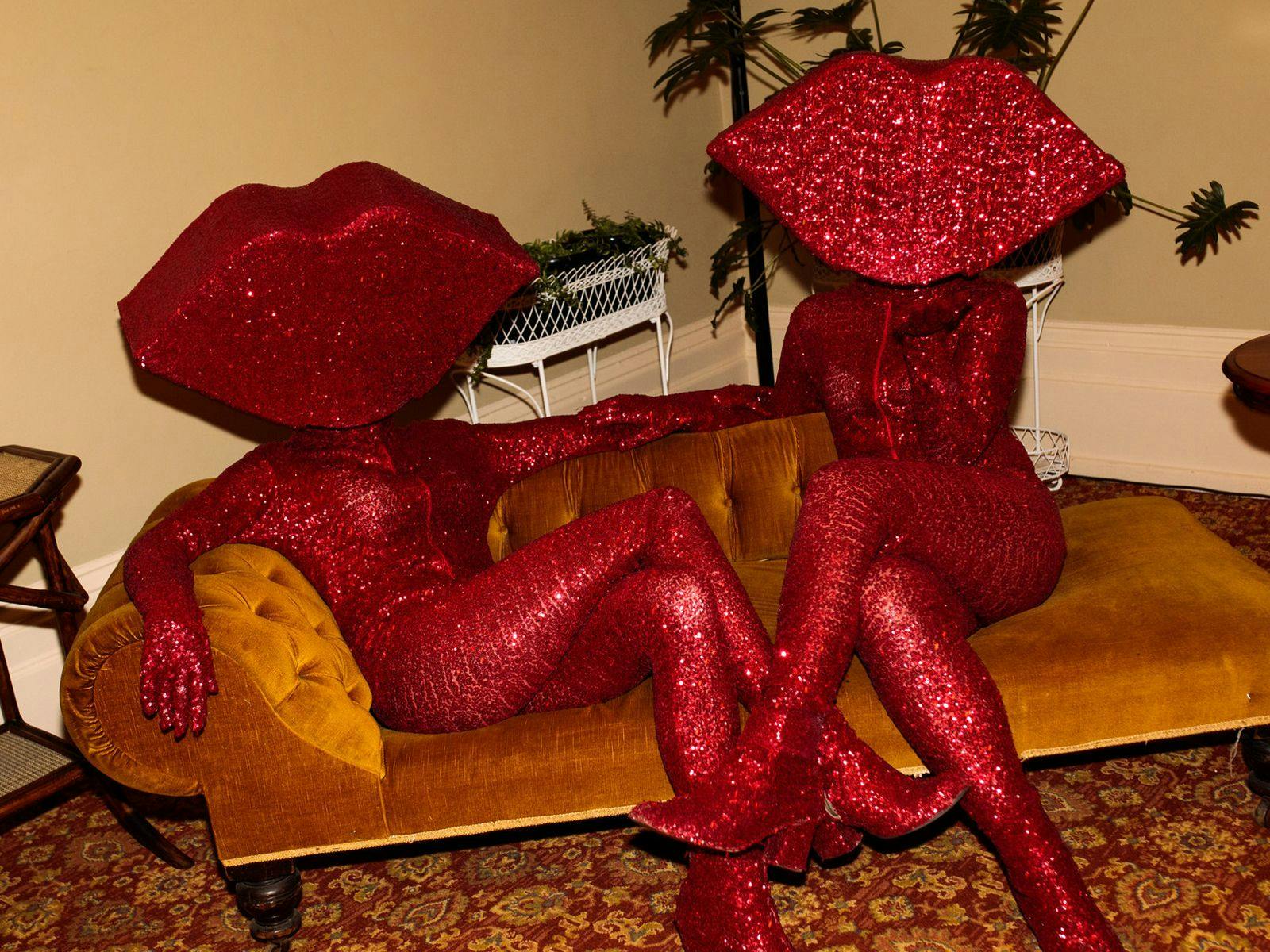 The Huxleys wearing sparkling red outfits sitting on a brown couch.