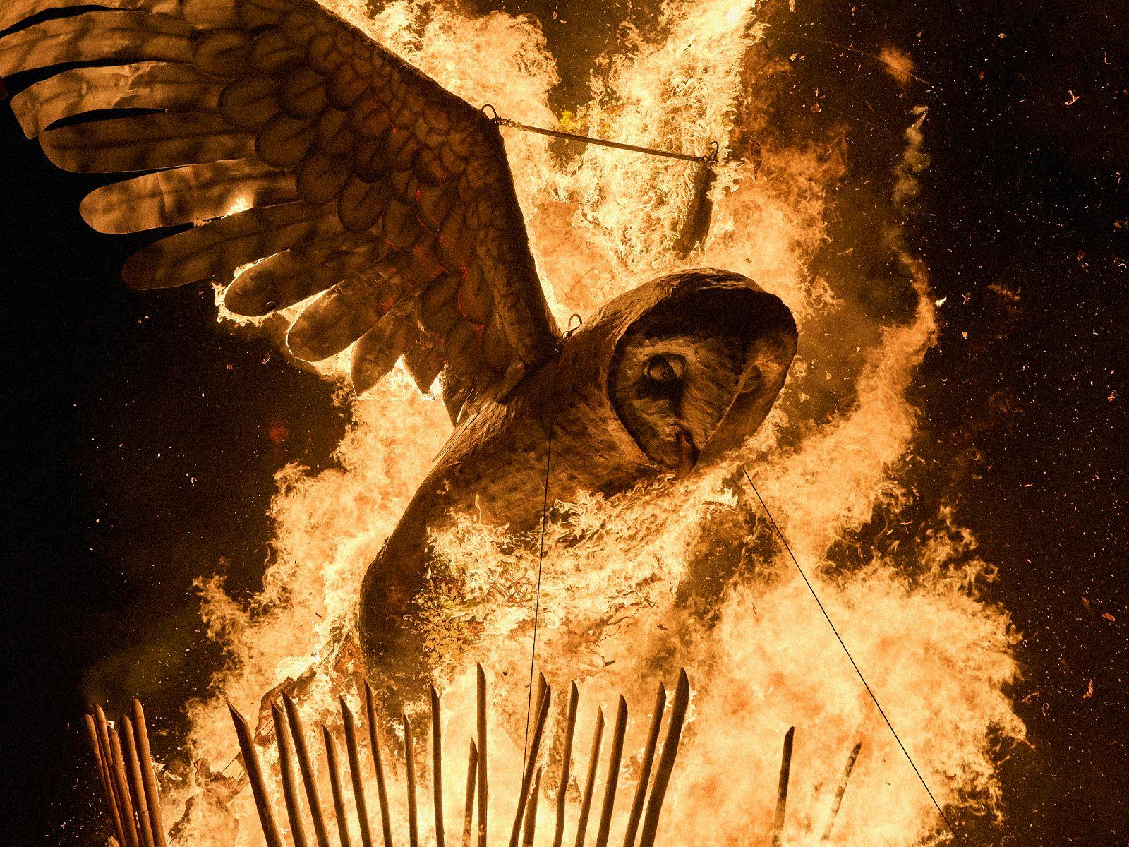A giant wooden owl burns furiously in the dark of night.