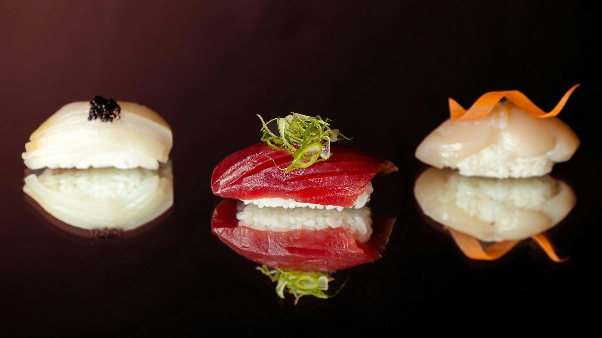 Three nigiri sushi sit on a mirror