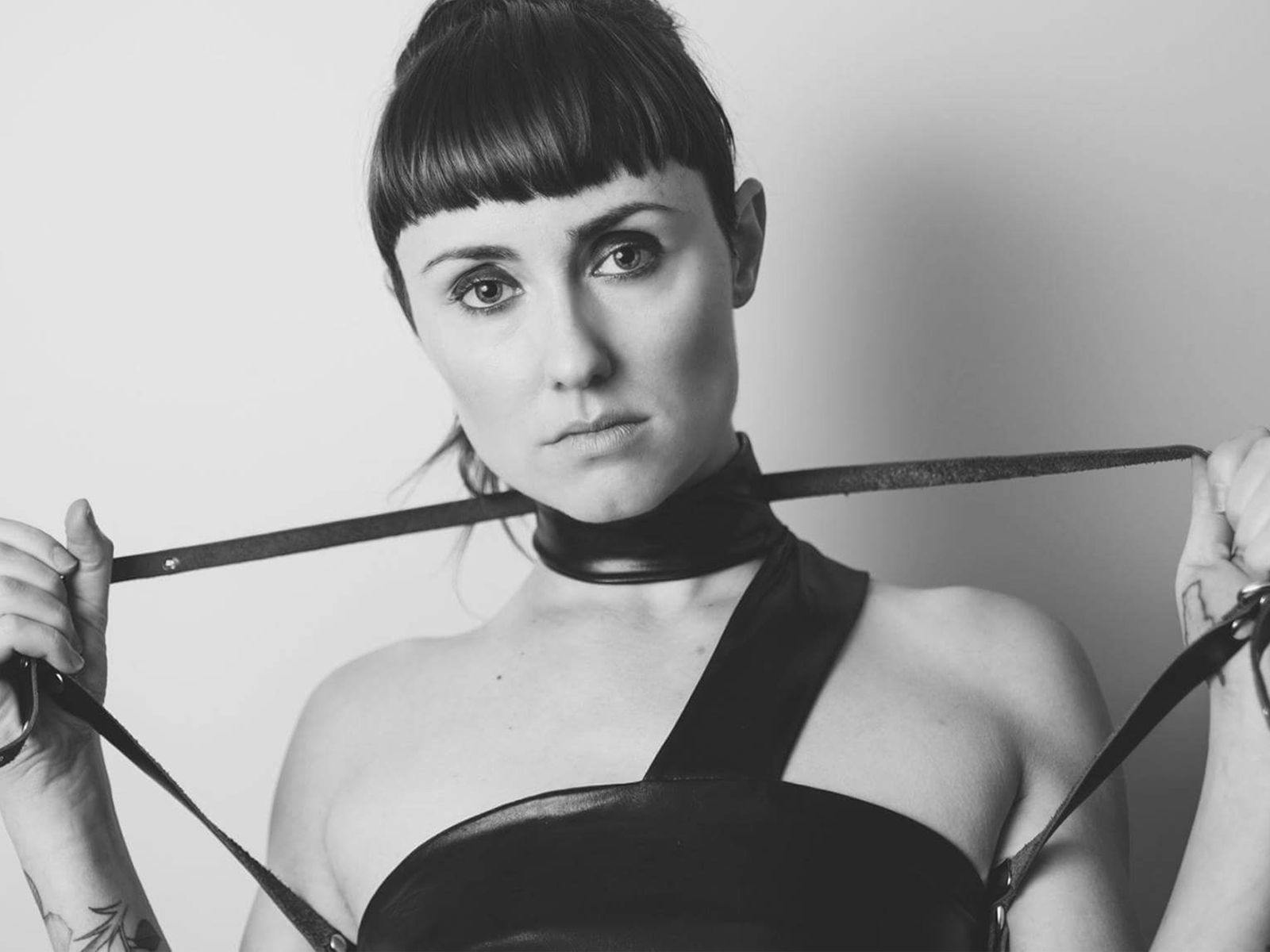 Estée Louder holds two ends of a belt tied around their neck.