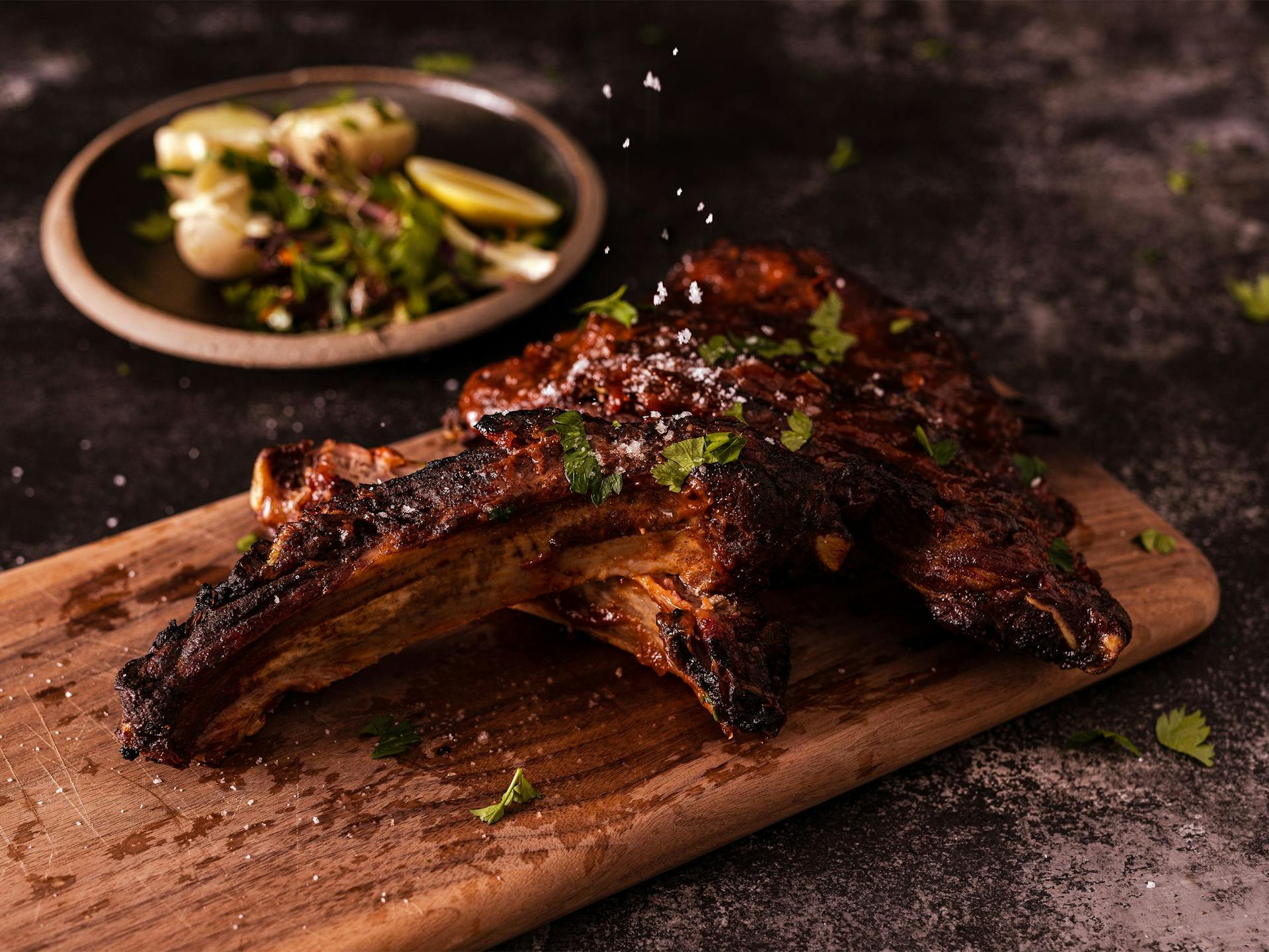 Pork ribs on a wooden board with salt sprinkled on top