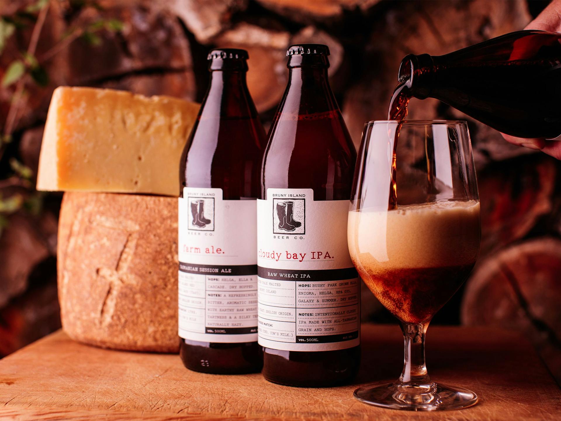Two Bruny Island beers sit next to a wheel of cheese and a glass of dark ale