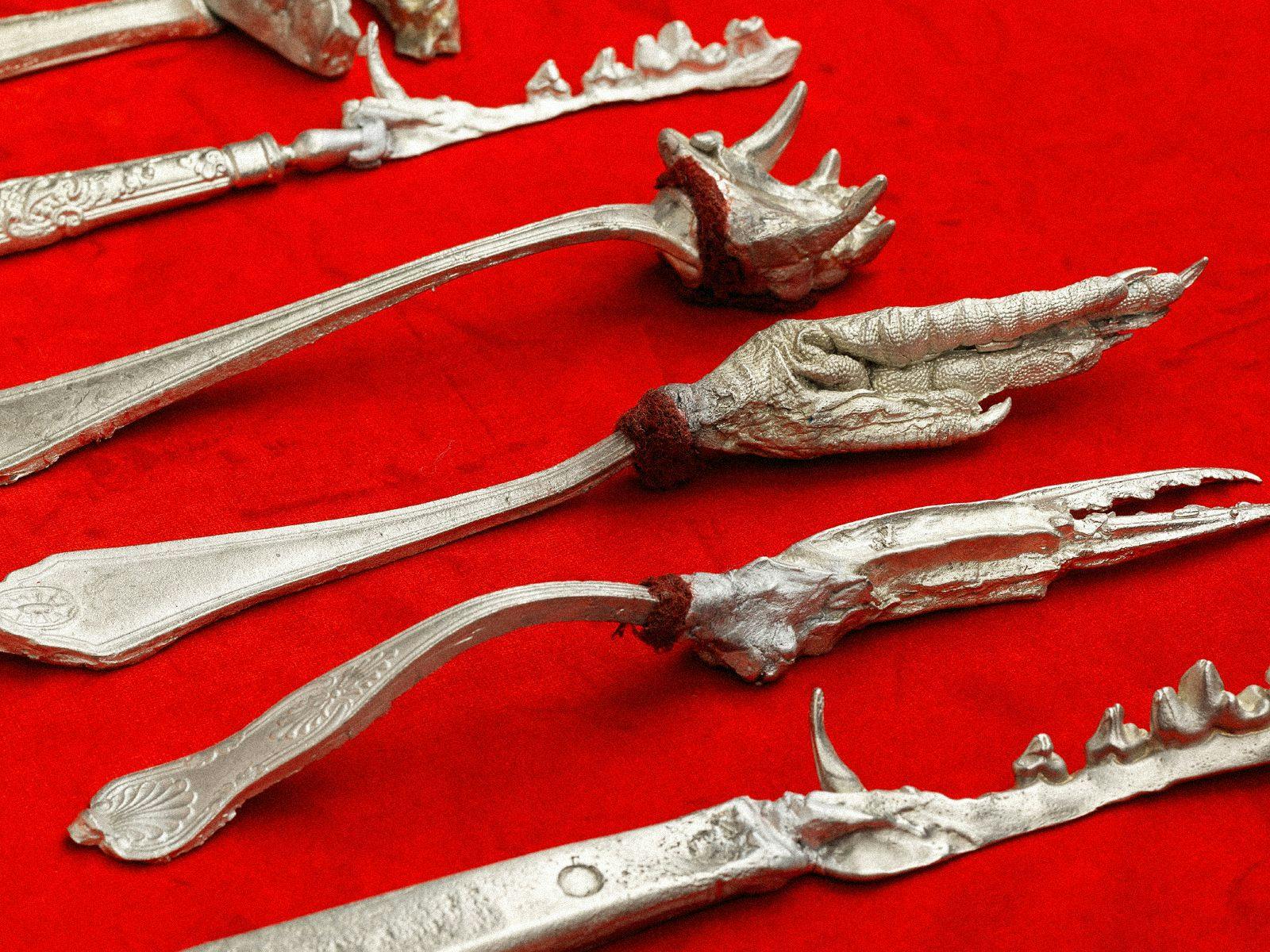 Several strange metal eating utensils, with animal features in place of blades or prongs.